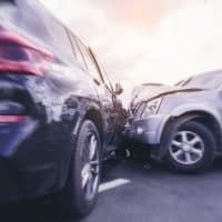 Car accident scene with two vehicles colliding, emphasizing the impact and potential injuries, relevant to factors affecting settlement values in Michigan personal injury claims.