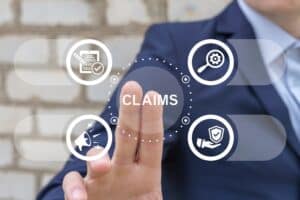 BusinessManWorkingOnVirtualTouchScreenPressesWordClaims | Detroit Personal Injury Attorneys Businessman gesturing with hand, surrounded by icons representing claims process, legal documentation, and personal injury law in Michigan.