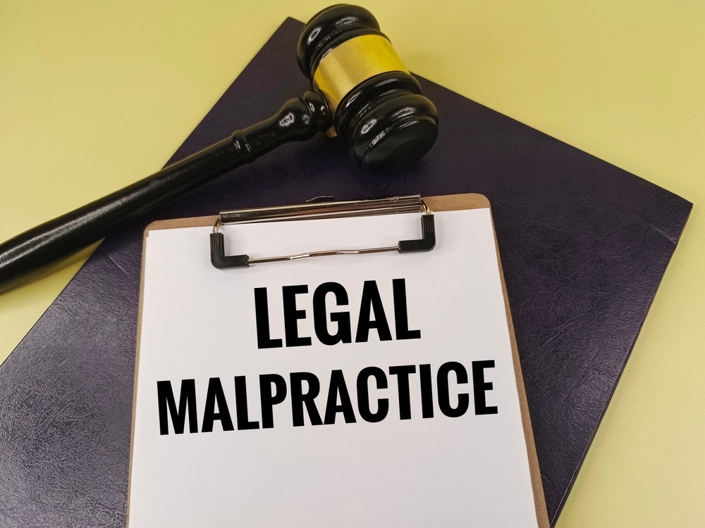 LegalMalpracticeTextOnClipboardWithJudgesGavelAndLaw