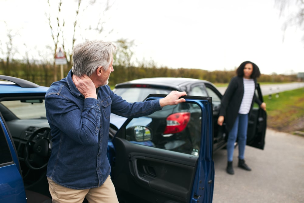 SeniorMaleAndYoungerFemaleDriversGetOutOfCars