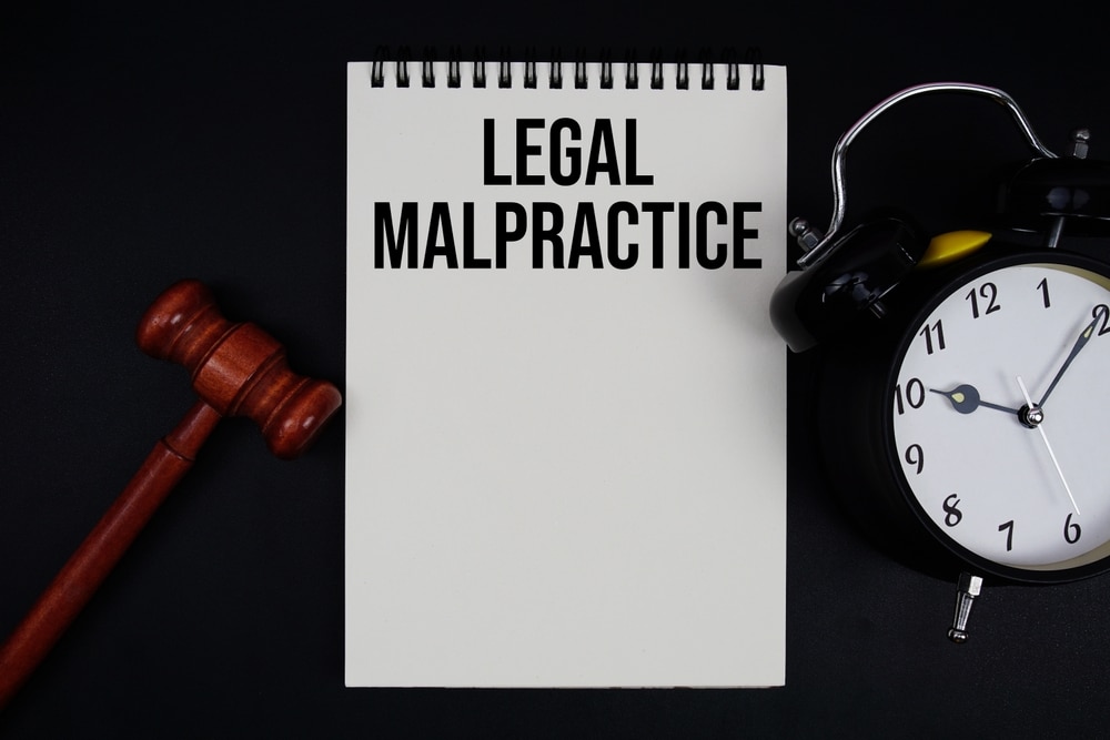 LegalMalpracticeTextWrittenOnNotepadWithGavelAndAlarm