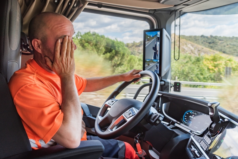 Fatigued truck driver in cab, representing driver fatigue and liability in Michigan accidents.